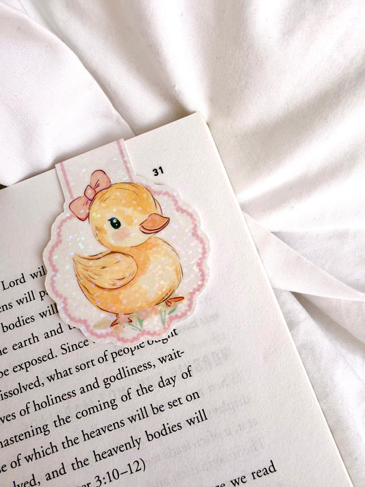 Illustrated duck bookmark on a book with a white fabric background